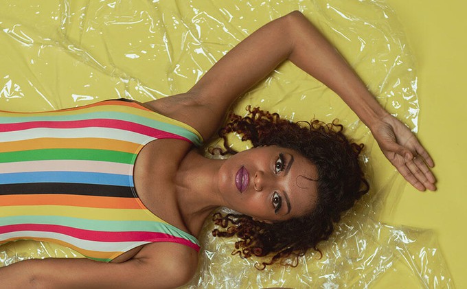 Model wearing traditional swimwear while lying down on a plastic sheet