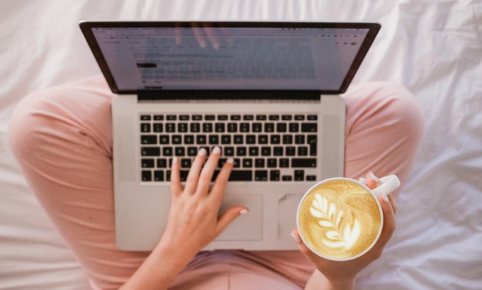 Crosslegged consumer reading one of the best newsletters on sustainable fashion while drinking a coffee