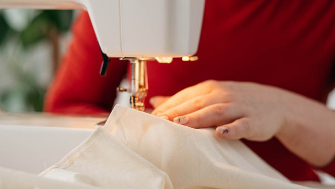 Garment worker sewing a clothing item in the middle of a sustainable fashion supply chain