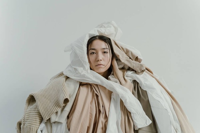 Consumer inside a pile of clothes to show why sustainable fashion is a myth