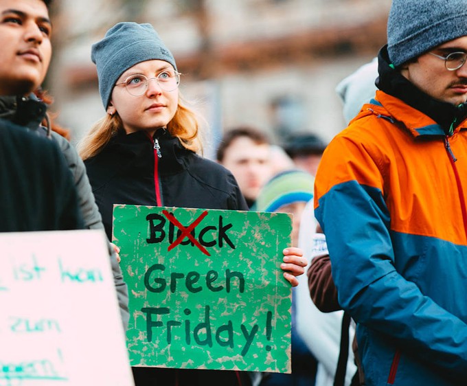 Woman holding a Green Friday sign for a more sustainable Black Friday initiative